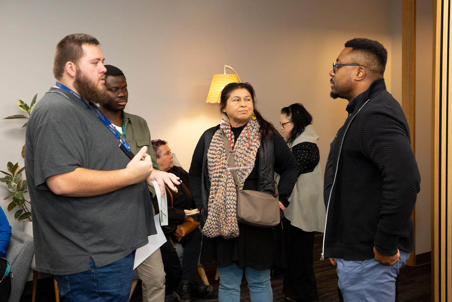 Two men and a woman talk and socialise in a modern, well-lit indoor space.