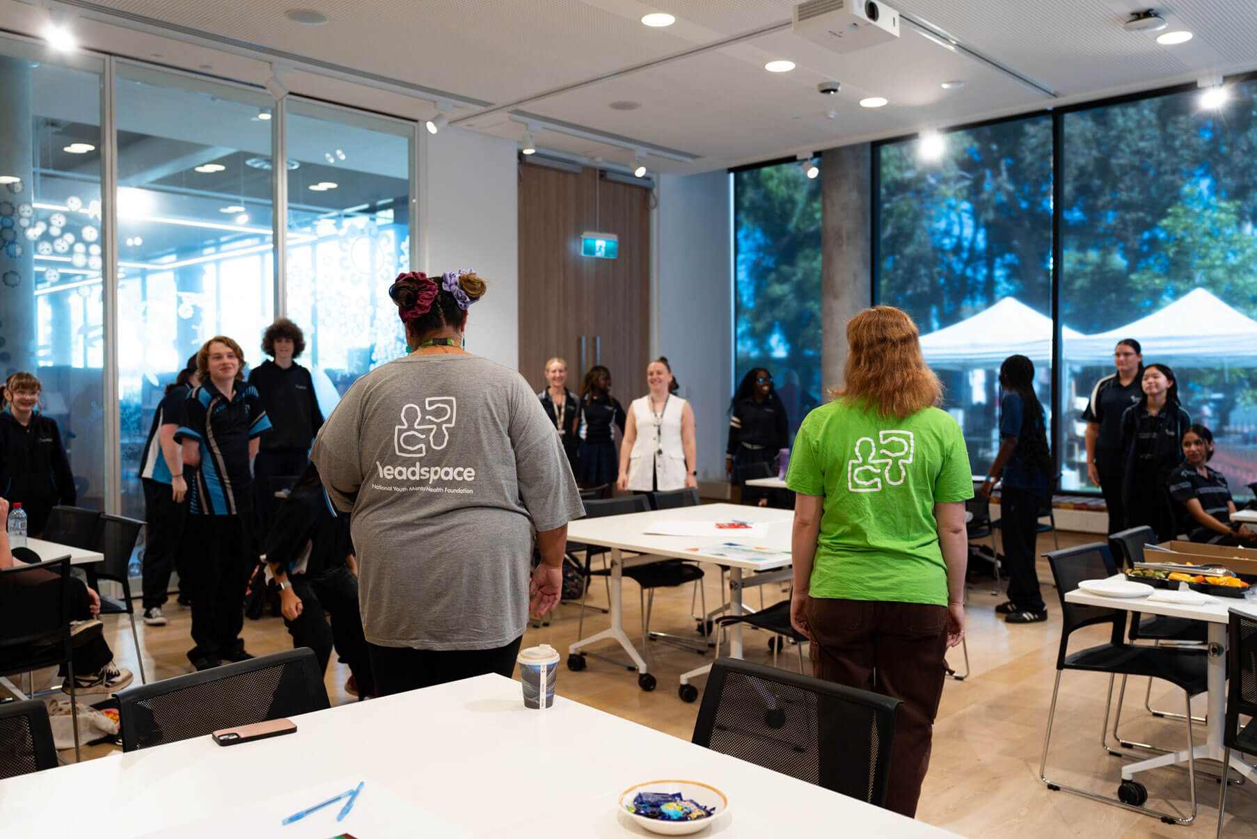 Two people in headspace t-shirts, stand in a room full of other people.